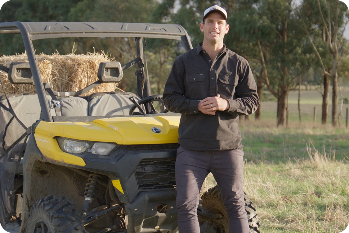 Tom Hawkins beside a Can-Am side-by-side on farmland