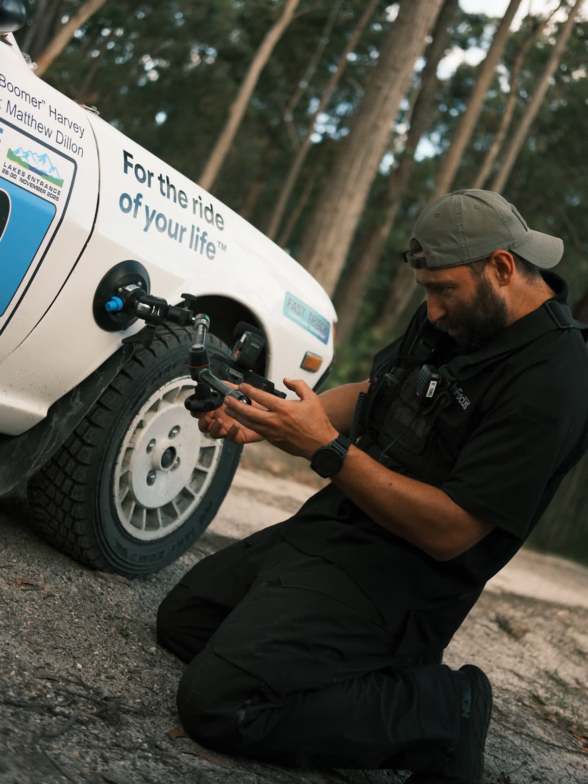 Shawn Peach sitting against the wheel of a rally car on a shoot